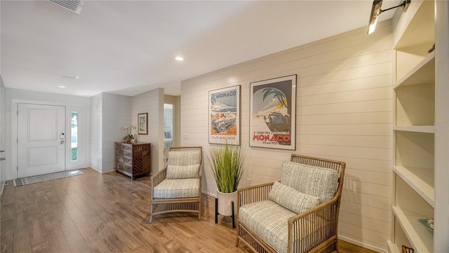 living area featuring hardwood / wood-style flooring and wooden walls