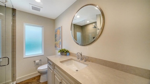 bathroom with hardwood / wood-style floors, vanity, toilet, and a shower with shower door