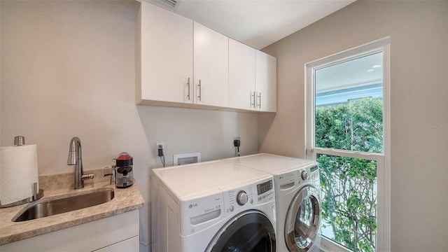 clothes washing area featuring cabinets, washing machine and clothes dryer, and sink