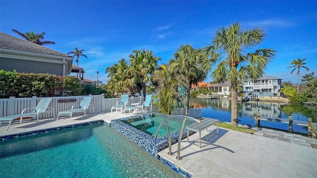 view of pool featuring an in ground hot tub, a water view, and a patio