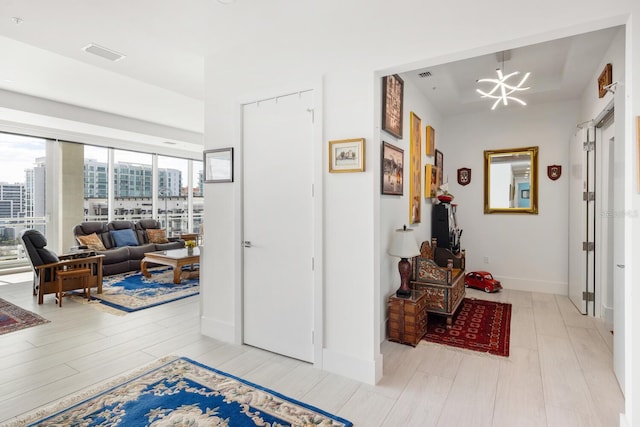 hall with an inviting chandelier and light hardwood / wood-style flooring