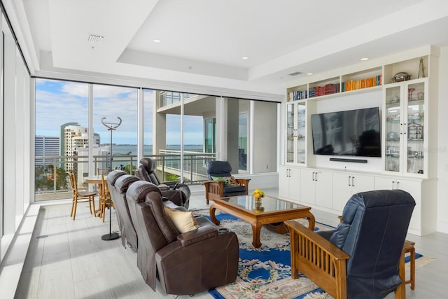 living room featuring plenty of natural light, expansive windows, and a raised ceiling