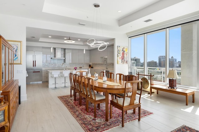 dining space featuring a tray ceiling and light hardwood / wood-style floors