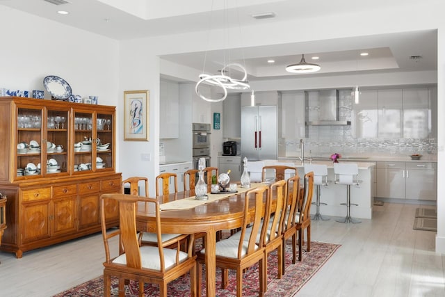 dining area featuring light wood-type flooring and a tray ceiling