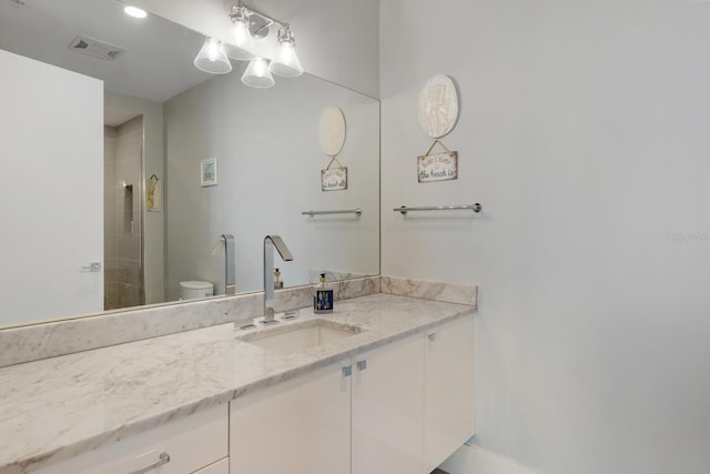 bathroom with a tile shower, vanity, and toilet