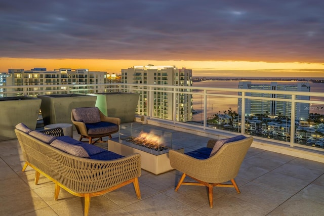 patio terrace at dusk featuring a water view and an outdoor living space with a fire pit