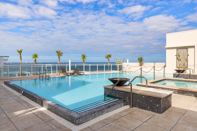 view of pool featuring a patio area, a water view, and a hot tub