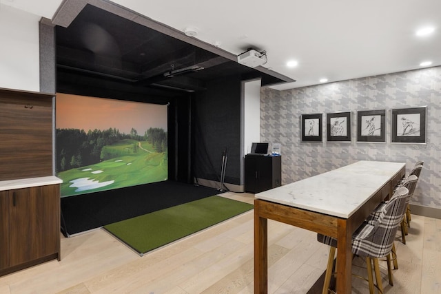 game room with light hardwood / wood-style floors and golf simulator