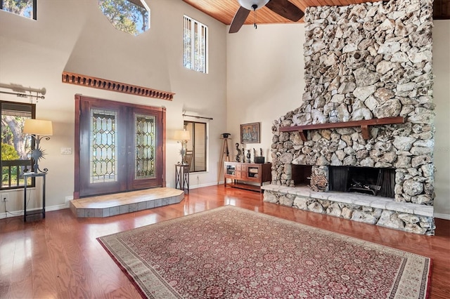 foyer entrance featuring high vaulted ceiling, a stone fireplace, hardwood / wood-style flooring, ceiling fan, and wood ceiling