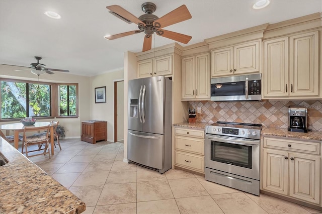 kitchen featuring cream cabinetry, decorative backsplash, light stone countertops, and stainless steel appliances