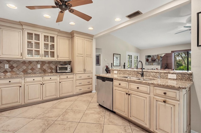 kitchen with decorative backsplash, stainless steel dishwasher, vaulted ceiling, sink, and cream cabinetry