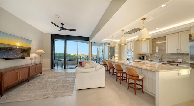 kitchen with a kitchen breakfast bar, tasteful backsplash, light stone counters, ceiling fan, and hanging light fixtures