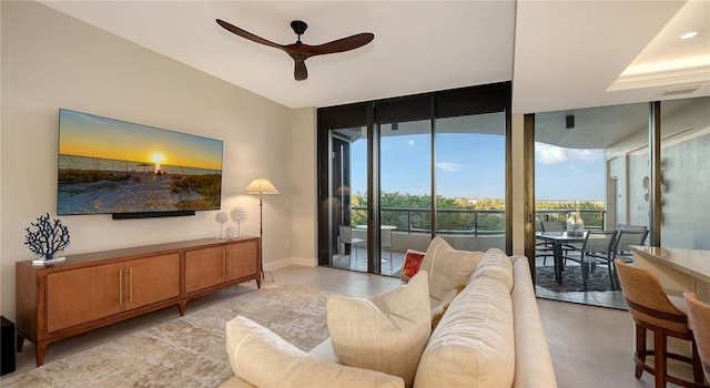 living room with ceiling fan, expansive windows, and a healthy amount of sunlight