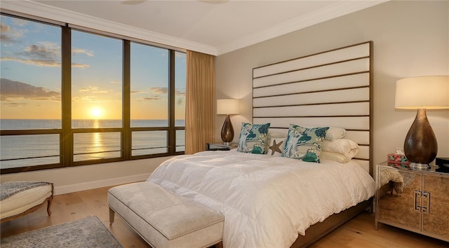 bedroom with wood-type flooring, a water view, and ornamental molding