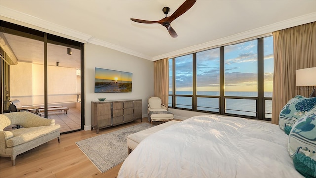 bedroom with ensuite bath, ceiling fan, expansive windows, wood-type flooring, and ornamental molding