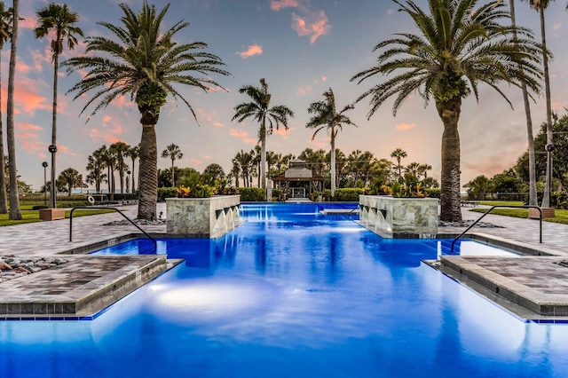 pool at dusk featuring pool water feature