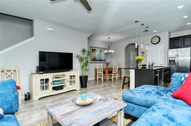 tiled living room featuring sink, ceiling fan with notable chandelier, and a textured ceiling