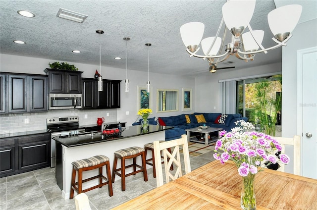 kitchen featuring a kitchen breakfast bar, backsplash, stainless steel appliances, an inviting chandelier, and a center island