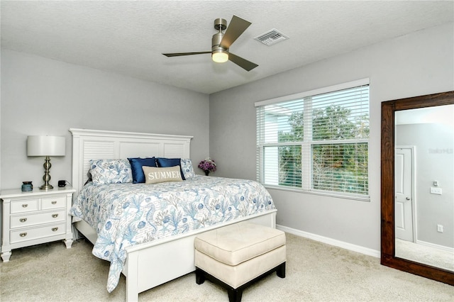 bedroom featuring ceiling fan, light colored carpet, and a textured ceiling