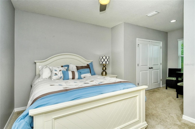 bedroom with light carpet, ceiling fan, and a textured ceiling