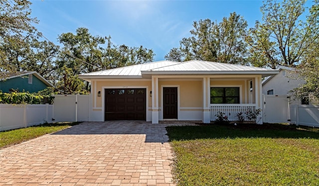 view of front of home featuring covered porch, a front yard, and a garage