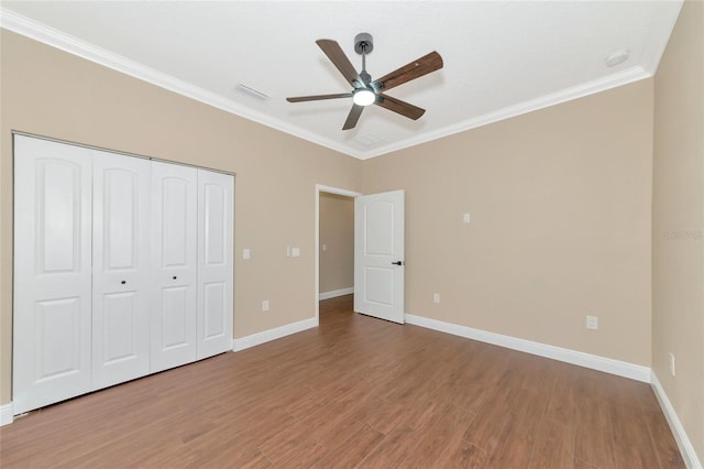 unfurnished bedroom with a closet, ceiling fan, crown molding, and hardwood / wood-style flooring