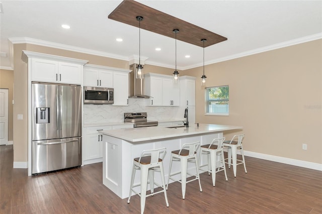 kitchen with white cabinets, appliances with stainless steel finishes, hanging light fixtures, and wall chimney exhaust hood