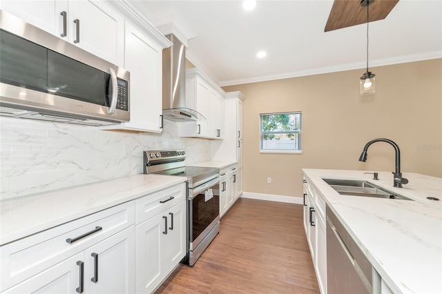 kitchen featuring pendant lighting, white cabinets, sink, light wood-type flooring, and appliances with stainless steel finishes