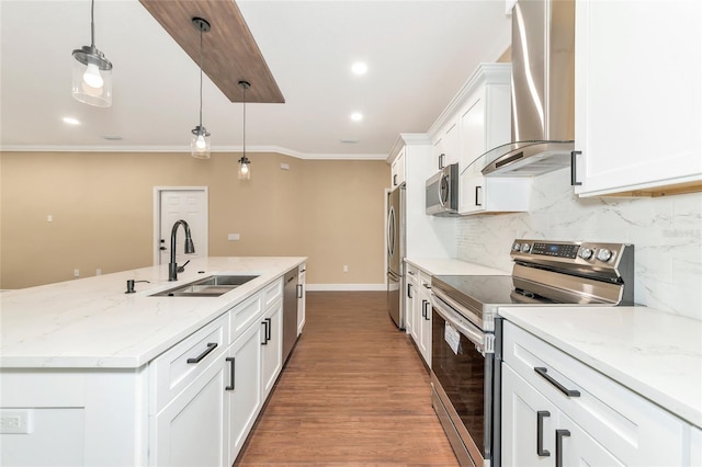 kitchen featuring appliances with stainless steel finishes, wall chimney exhaust hood, sink, pendant lighting, and white cabinetry