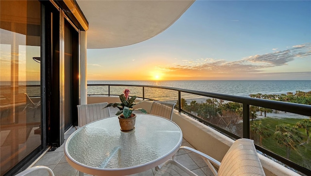 balcony at dusk featuring a water view