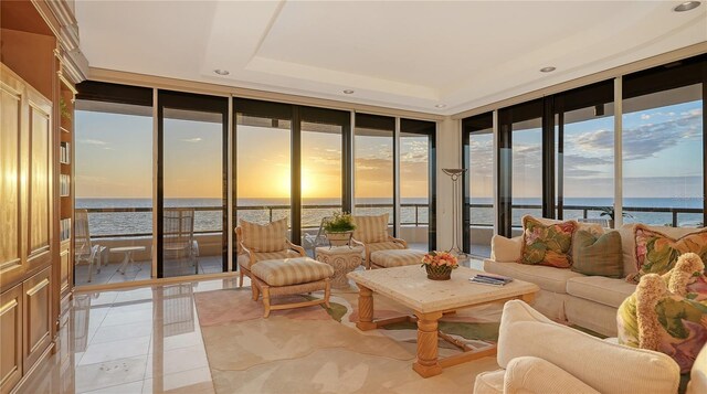 sunroom featuring a water view and a tray ceiling