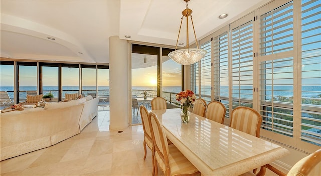 dining area featuring floor to ceiling windows, a water view, light tile patterned floors, and a tray ceiling