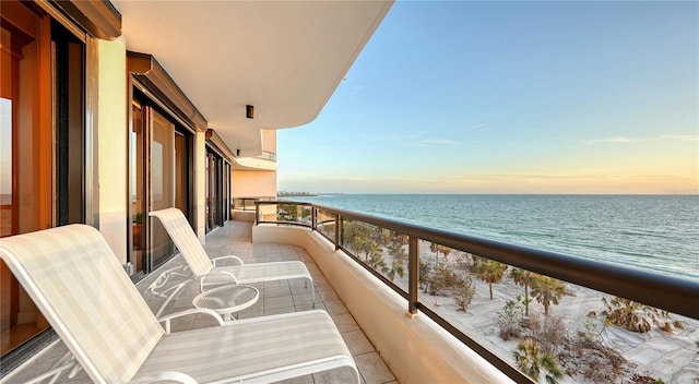 balcony at dusk with a water view and a beach view