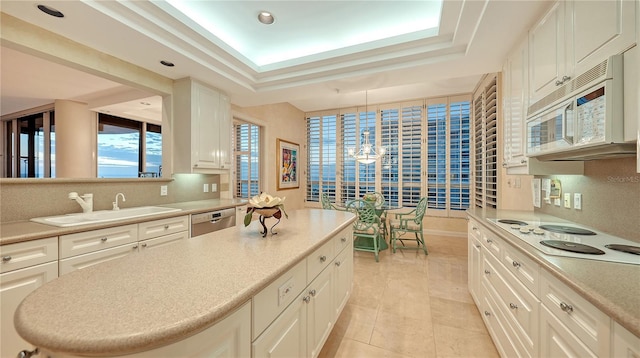 kitchen featuring white appliances, a raised ceiling, sink, white cabinetry, and hanging light fixtures