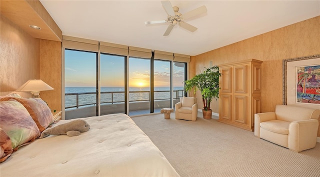 carpeted bedroom featuring access to exterior, ceiling fan, a water view, and multiple windows