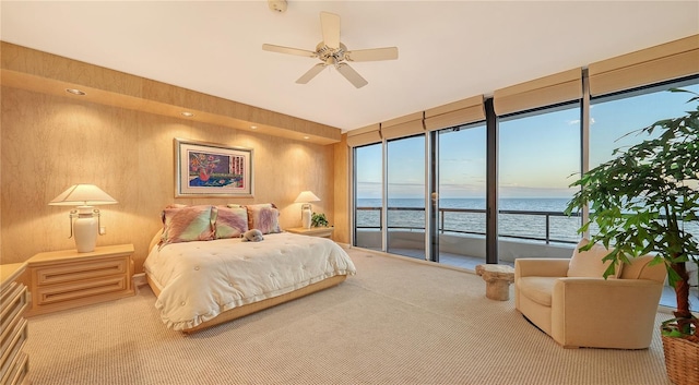 carpeted bedroom with access to exterior, a water view, and ceiling fan