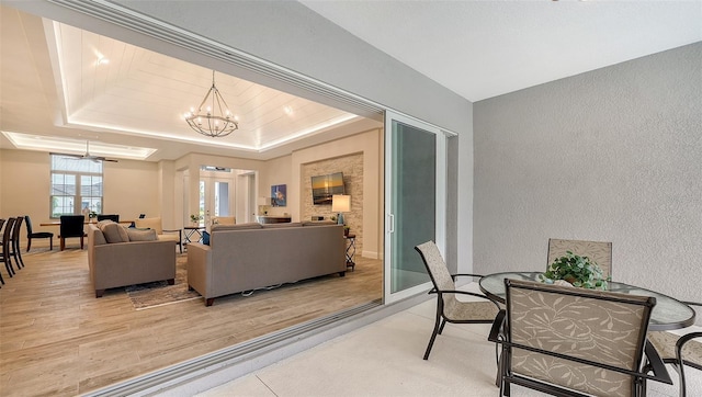 living room featuring a raised ceiling, wood-type flooring, and ceiling fan with notable chandelier