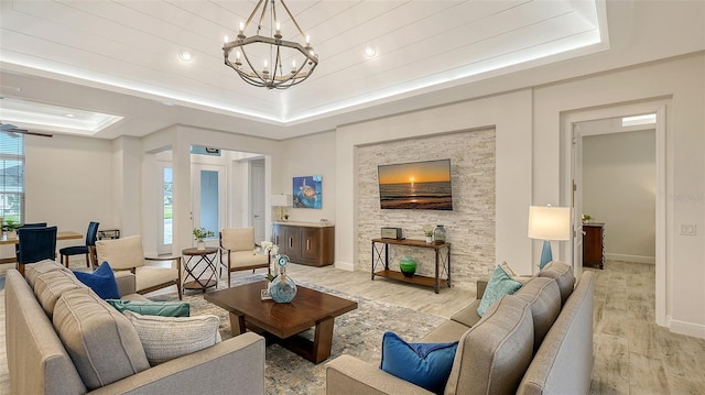 living room featuring light hardwood / wood-style floors, a raised ceiling, and a chandelier