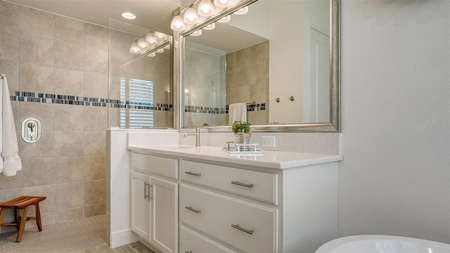 bathroom with tiled shower and vanity