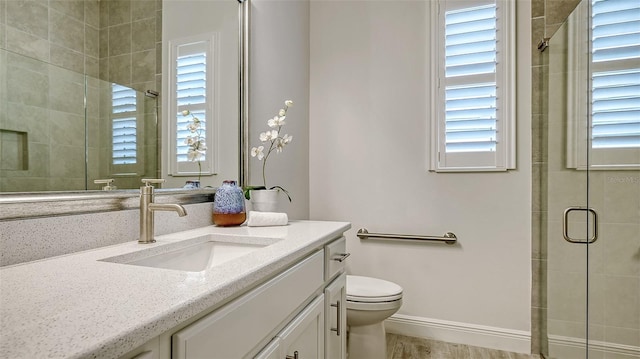 bathroom with hardwood / wood-style floors, vanity, toilet, and a shower with shower door