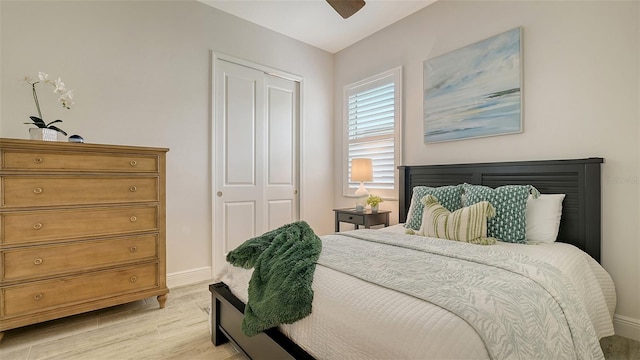 bedroom with ceiling fan, a closet, and light hardwood / wood-style flooring