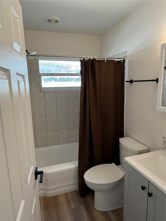 full bathroom featuring hardwood / wood-style floors, vanity, shower / bath combination with curtain, and toilet