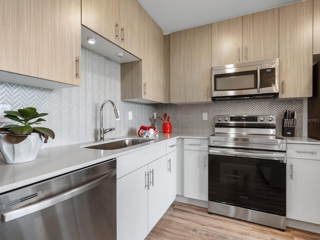 kitchen with sink, stainless steel appliances, light brown cabinetry, and light hardwood / wood-style flooring