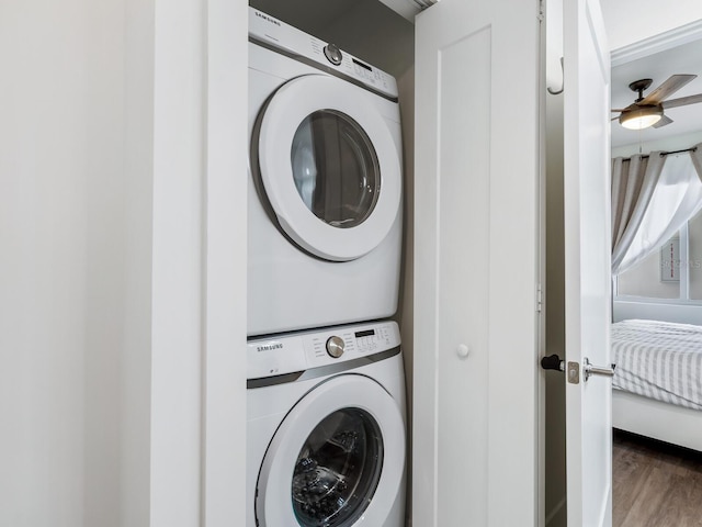 laundry room featuring hardwood / wood-style floors and stacked washer and clothes dryer