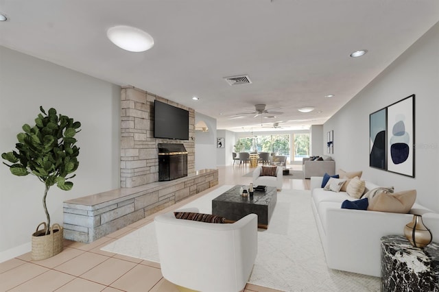 tiled living room featuring ceiling fan and a fireplace