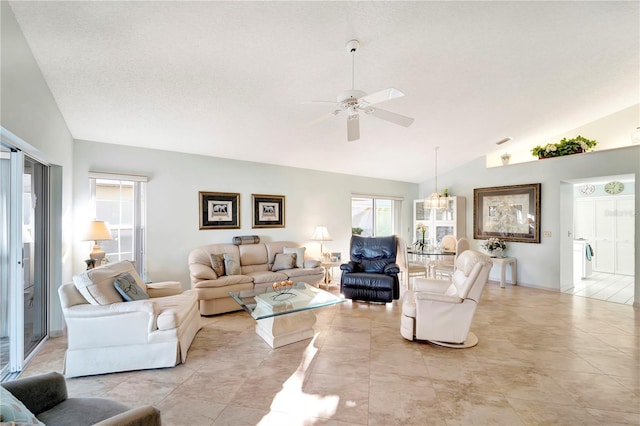 living room featuring ceiling fan, lofted ceiling, a textured ceiling, and light tile patterned floors