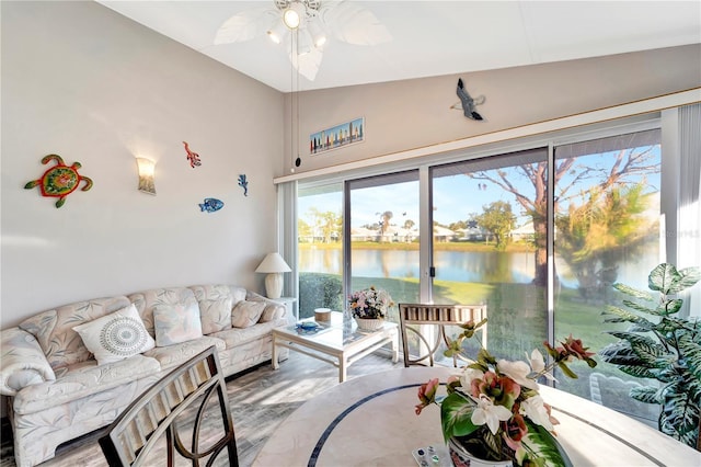 sunroom / solarium featuring a water view, lofted ceiling, and ceiling fan