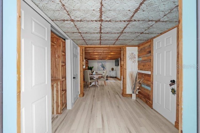 hall featuring light wood-type flooring and wood walls