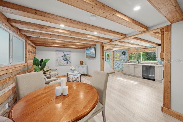 dining area featuring beamed ceiling, light hardwood / wood-style floors, and sink