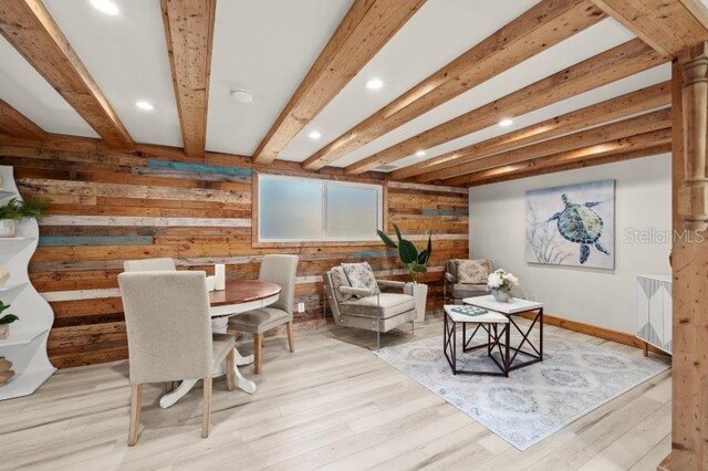 sitting room with beamed ceiling, light hardwood / wood-style floors, and wooden walls